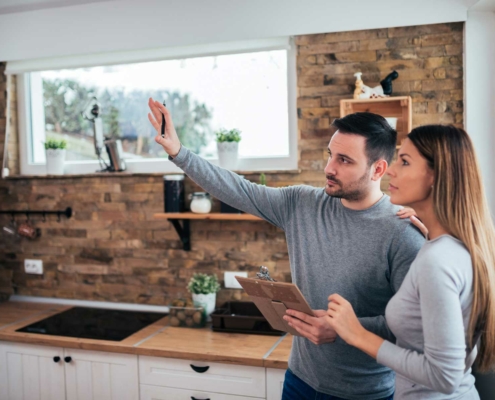 An inspector pointing out something to a client in the kitchen